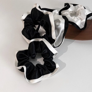 Gros plan du chouchou en satin noir et blanc avec texture lisse et design élastique