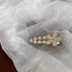 Détail d'une pince à cheveux dorée élégante avec fleur de perles et perles dégradées sur papier