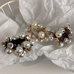 Detailed close-up of elegant pearl and rhinestone elastic hair ties in gift packaging