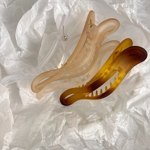 Detailed macro view of matte resin banana hair claws in white pink and amber colors