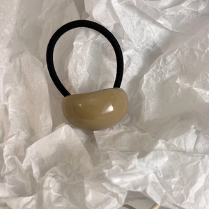 Close-up of minimalist hair tie featuring a smooth oval resin bead on black elastic band