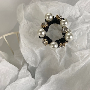 Detailed macro view of elastic hair tie with white faux pearls and gold-set crystal rhinestones