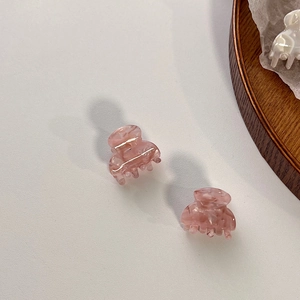 Detailed close-up of small pink marble acetate hair claws with a polished resin finish