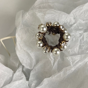 Detail of coffee brown elastic hair tie featuring white pearls and golden claw rhinestones