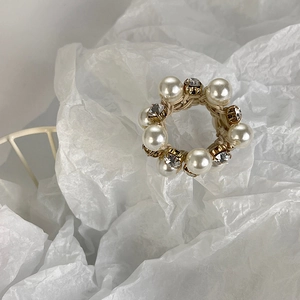 Detailed macro shot of elegant pearl hair tie with gold-clawed rhinestones