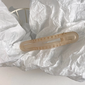 Detail of nude matte hair claw clip with embossed dots and hollow design on white mesh