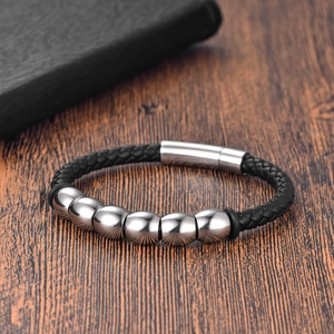Bracelet en cuir tressé pour hommes avec perles argentées sur fond en bois naturel