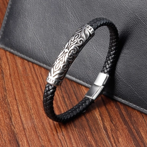 Macro view of braided black leather bracelet featuring a silver engraved metal totem tube
