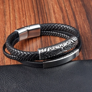 Close-up of multilayer leather bracelet with engraved silver magnetic clasp and metal charms