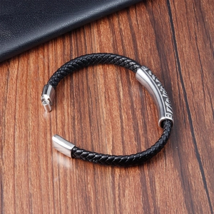 Macro view of braided leather bracelet featuring engraved metal tube and magnetic clasp