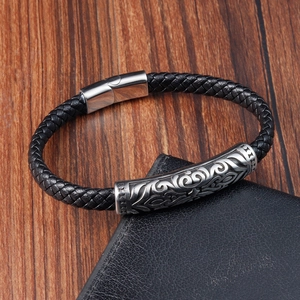 Detail of black woven leather bracelet featuring a silver metal cylinder and magnetic clasp