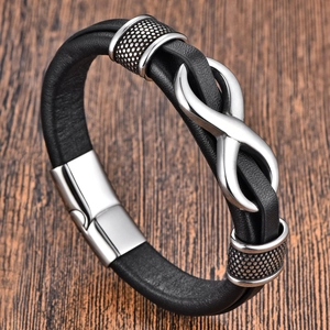 Men's black leather infinity bracelet with polished silver magnetic clasp on wood