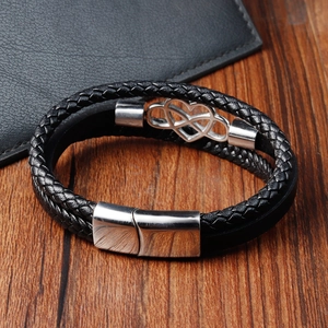 Detail of black braided leather bracelet featuring a silver infinity heart metal charm