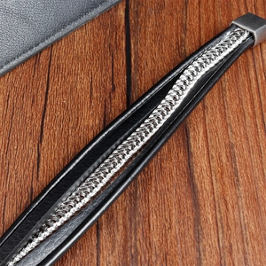 Macro view of men's leather bracelet with silver metal chain weave and secure clasp