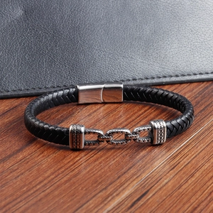 Detail eines schwarzen Lederarmbands mit silbernem Magnetverschluss auf dunklem Hintergrund