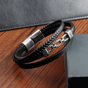 Detail eines mehrlagigen schwarzen Lederarmbands mit Unendlichkeitssymbol und Magnetverschluss