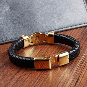 Men's double-layered black woven leather bracelet with gold interlocking rings on wood