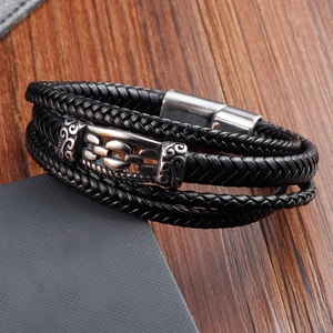 Detail of multi-layer black braided leather bracelet with vintage metal scroll buckle
