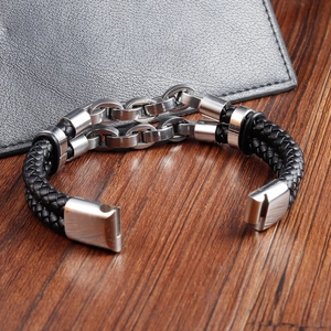Close-up of black braided leather and stainless steel chain on a dark wooden surface