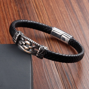 Detail of woven black leather bracelet showing vintage engraved metal and magnetic clasp
