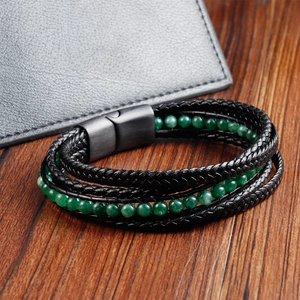 Macro shot of black braided leather bracelet with green beads and magnetic clasp