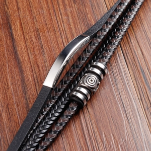 Macro detail of braided leather layers with polished steel beads on wood surface