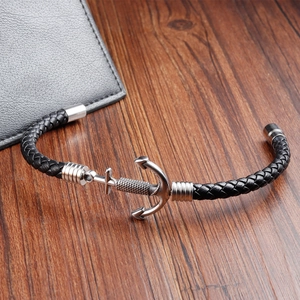 Close-up of a silver anchor charm on a black braided leather bracelet for men