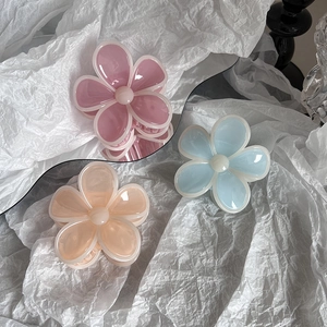 Three jelly-colored flower hair claws in pink, blue, and orange on a white backdrop