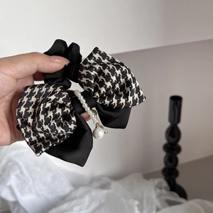 Detail of French houndstooth bow hair tie featuring elegant white pearl center ornament