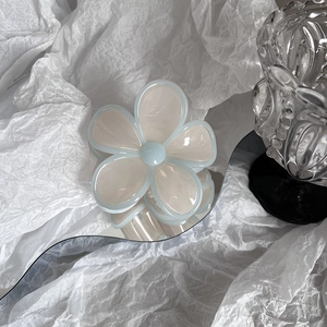 Close-up of cream white and light blue flower hair claw clip on wave mirror
