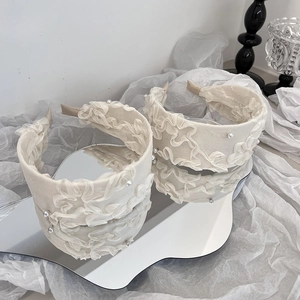 Détail d'un serre-tête élégant en mousseline crème avec volants et perles blanches