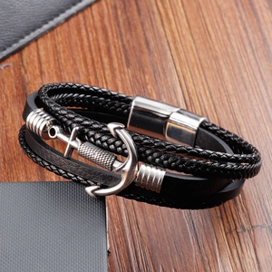 Detailed view of men's leather anchor bracelet with magnetic clasp on wooden table