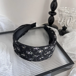 Gros plan sur un serre-tête noir en tissu avec de petites fleurs violettes et jaunes