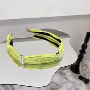 Close-up of a lime green pleated fabric headband with double rows of elegant pearls