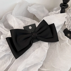Détail du nœud papillon multicouche en satin noir avec une texture lisse et élégante