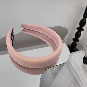 Gros plan d'un serre-tête large rembourré rose avec satin texturé sur miroir ondulé