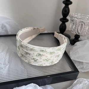 Détail du serre-tête plissé large avec motif floral vert sur tissu beige doux