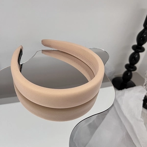 Détail d'un serre-tête en éponge beige avec tissu sergé sur une surface miroir