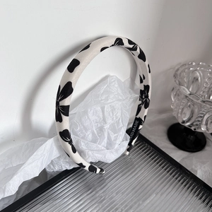 Detailed close-up of a handmade fabric headband featuring elegant black floral patterns