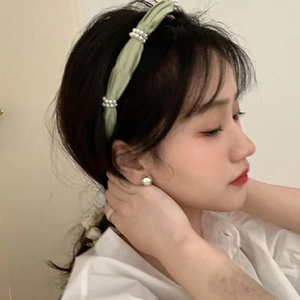Elegant green pleated fabric headband with pearl accents worn by a model in a side profile view