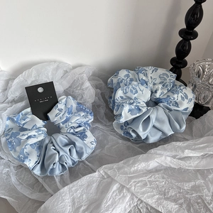 Elegantes Set aus blauen Scrunchies mit Blumenmuster und Satin auf weißem Hintergrund