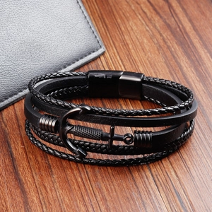 Detailed macro view of black braided leather bracelet with large metal anchor charm