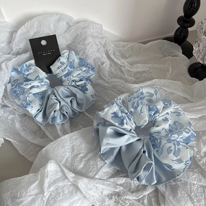 Set aus blauen Blumen- und Satin-Haargummis auf weißem Grund für elegantes Styling