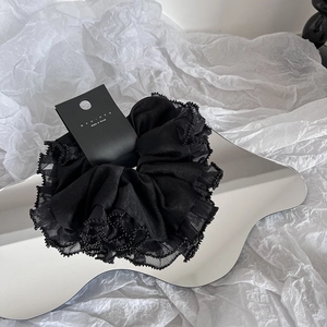 Gros plan sur un chouchou en organza noir avec perles sur un miroir ondulé