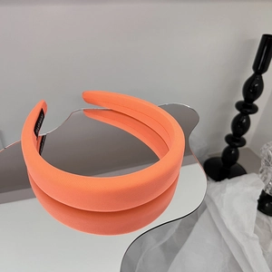 Détail du serre-tête orange rembourré avec étiquette artisanale et texture en sergé