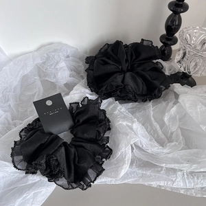 Chouchous élégants en tulle noir avec bordure perlée sur un fond texturé minimaliste