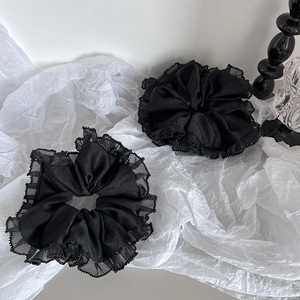 Vue détaillée de deux grands chouchous noirs avec bordure en dentelle et détails de perles