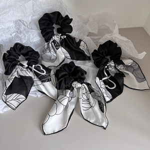 Detail view of four elegant black and white floral satin scrunchies with long silk ribbons