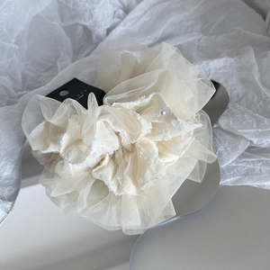 Elegant cream mesh scrunchie with pearls on a wavy mirror tray for hair styling