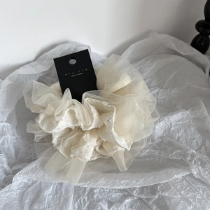 Detail of a large creamy white layered mesh scrunchie featuring a center pearl accent